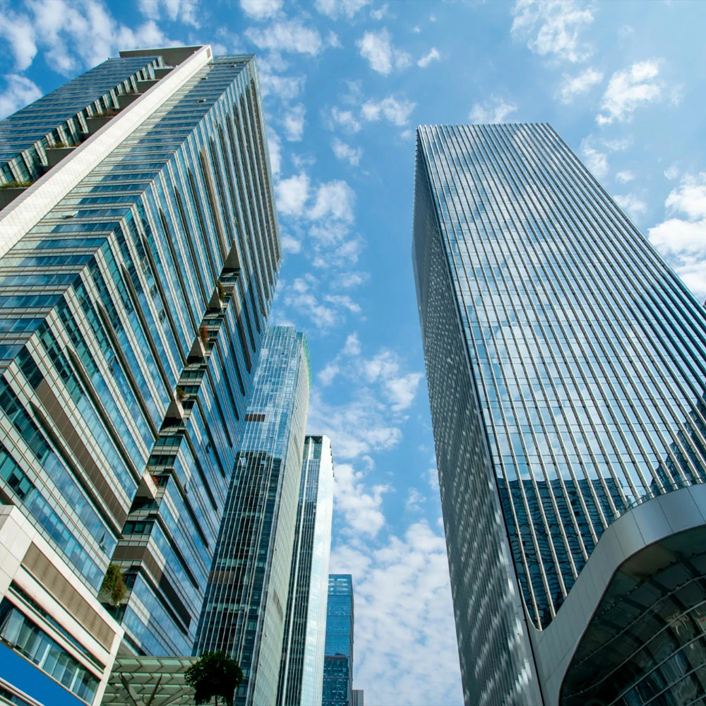 Tall corporate skyscrapers against a blue sky with scattered clouds.