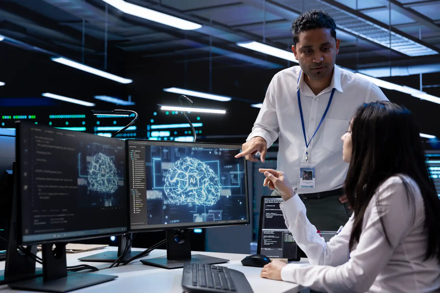 AI developers discussing a digital brain visualization on dual monitors- IT & Cybersecurity Services for SMBs