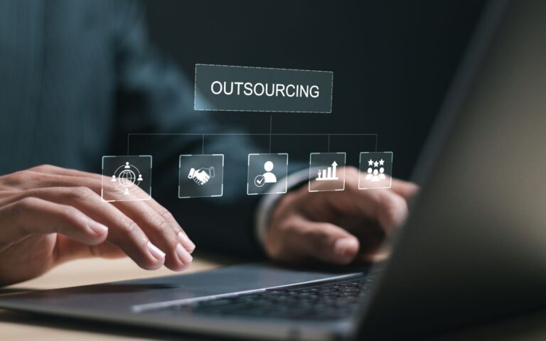 IT outsourcing image of hands on a laptop with a holographic interface displaying icons for global reach, collaboration, and growth. benefits of outsourcing it services